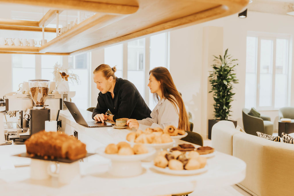 Two members working together at the café bar in the lounge at Vallist Finlaison House, Holborn
