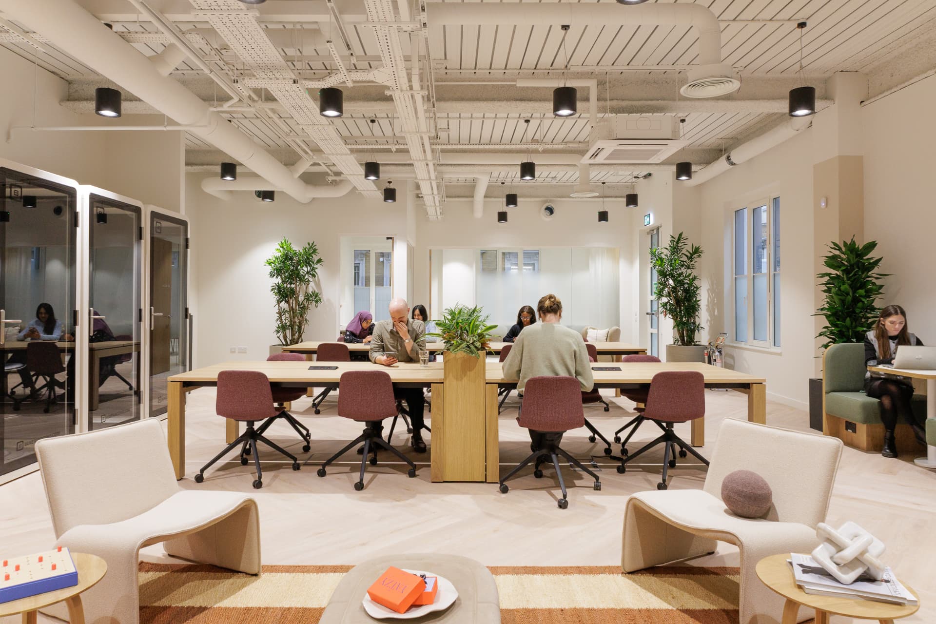 Professionals working at shared desks beside lounge seating and phone booths at Vallist Finlaison House